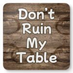 Square coaster with image of wood with water rings on it and text that says 'Don't Ruin My table'.