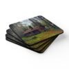 Set of 4 coasters with an image of a log cabin in a forest printed on them. Shown stacked on a table.