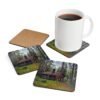 Set of 4 coasters with an image of a log cabin in a forest printed on them. Shown with a mug for scale.