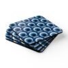 Set of 4 square coasters with a blue and white mid century modern circle print design. Shown stacked on a table.