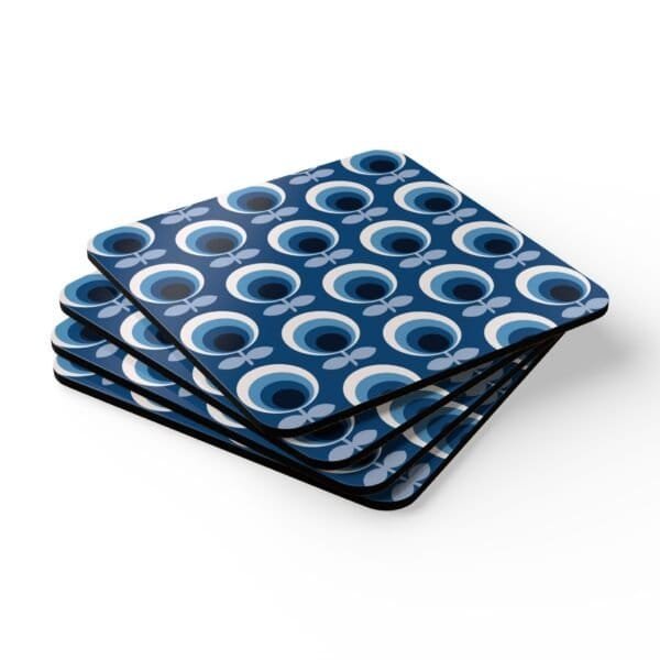 Set of 4 square coasters with a blue and white mid century modern circle print design. Shown stacked on a table.