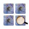 Set of 4 coasters with abstract art print in shades of purple, black and gold. Shown with a mug for scale.