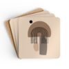 Set of four square coasters with minimalist neutral design in shades of brown, tan and black. Shown stacked on a table.