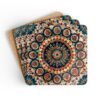 Set of 4 square coasters with image of a red, navy blue and turquoise mandala print. Shown stacked on a table.