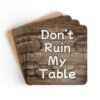 Set of four square coasters with image of wood with water rings on it and text that says 'Don't Ruin My table'. Shown stacked on a table.