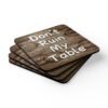Set of four square coasters with image of wood with water rings on it and text that says 'Don't Ruin My table'. Shown stacked on a table.