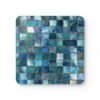 Colorful square mosaic design in shades of turquoise and teals coaster flat on table.