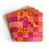Stack of square cork‑backed coasters featuring a bold geometric pattern in pink, orange, and red tones. The design includes circles, triangles, and abstract shapes arranged in a retro grid style.